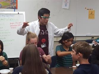 Science teacher in white coat and glasses teaching class