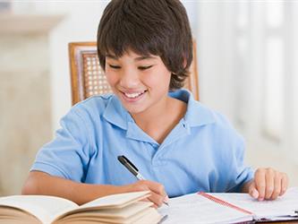 boy in blue shirt writing in books