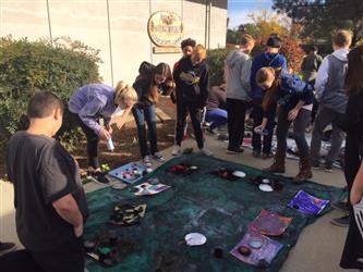 Students outside painting solar systems