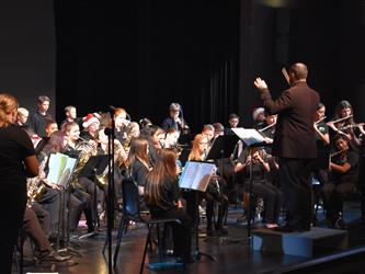Band students on stage performing with teacher conducting