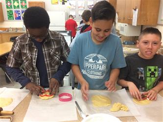 three boys smiling and preparing food