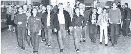 Black and White image of students walking down a hallway, clothing circa 1950s